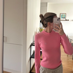 Rosa ribbad tröja från Levis - Säljer en rosa ribbad långärmad tröja från Levis. Tröjan har en tight passform och rund halsringning, med en liten logotyp på bröstet. Perfekt för dig som gillar stilrena och bekväma plagg.