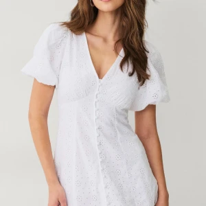 Vit kort klänning från Gina Tricot - Supersöt vit klänning från Gina Tricot i storlek XS. Klänningen har puffiga korta ärmar, v-ringning och knappar framtill. Den är sydd i bomull med broderade blommor och har volang nedtill för extra flow. Den är endast använd en gång och är som ny! Perfekt till skolavslutningen och sommaren!💞💞