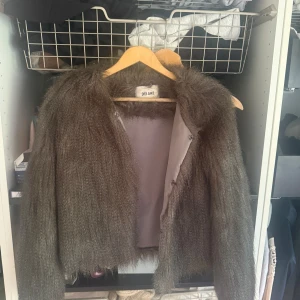 Grå pälsjacka från Dry Lake - Säljer en fluffig grå pälsjacka från Dry Lake. Jackan har lång ärm, rund halsringning och stängs med dolda knappar framtill. Super fin och gosig till hösten men fungerar även på vintern med en stickad tröja under då den är ganska varm. Jag köpte den på Sellpy för 700 för ca ett år sedan men nypris är runt 1500.