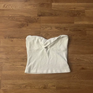 Vit bandeau tubtopp med twist - Säljer en vit bandeau tubtopp med twistad detalj framtill från SHEIN. Använd ett fåtal gånger men är tyvärr för liten i bysten. 