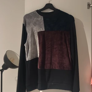 Colorblock sweatshirt från La Vichy S - Säljer en snygg långärmad sweatshirt från La Vichy i storlek S. Tröjan har coola färgblock i svart, grått och vinrött framtill, med mjuk sammetspanel och en patch på ärmen. Perfekt för dig som gillar streetstyle och unika detaljer.