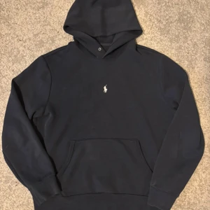 Svart hoodie från Polo Ralph Lauren - Klassisk svart hoodie från Polo Ralph Lauren med broderad logga mitt på bröstet. Nypris: ~ 1600 | Vi säljer för 899. Väldigt bra skick, inga fläckar eller liknande. Storlek M. Tveka inte att höra av er med prisförslag eller frågor!