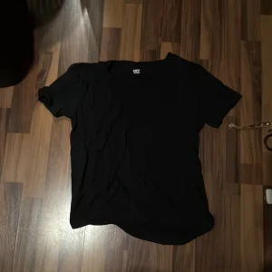 Svart t-shirt från 157 - En enkel svart t-shirt från 157 med korta ärmar och rund hals. Perfekt för dig som gillar basic och stilrena plagg. T-shirten är gjord i mjuk bomull och har en normal passform som funkar till det mesta.