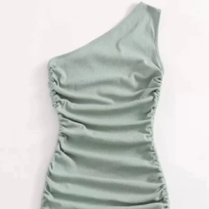 Grön oneshoulder klänning - Snygg ljusgrön kortklänning med oneshoulder-design och ribbad struktur. Klänningen har rynkade sidor med snörning nedtill som ger en cool och figurnära passform. 