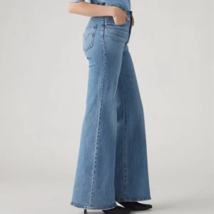 Levi's Ribcage Bell blå jeans - Säljer ett par Levi's Ribcage Bell jeans i klassisk blå denim. De har hög midja och riktigt utsvängda ben för en retro vibe. Jeansen är tillverkade i bomull och har fem fickor samt Levi's ikoniska läderpatch bak. Perfekta för dig som gillar statement-jeans! storlek 30x34