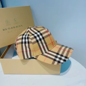 Burberry rutig keps i beige - Snygg keps från Burberry i klassiskt beige rutigt mönster med svarta, vita och röda linjer. Kepsen har böjd skärm och justerbar passform. Perfekt accessoar för att lyfta din outfit med en lyxig touch.