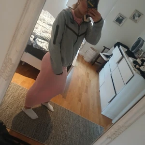 Grå Nike tech  - Säljer en grå niketech  med svart dragkedja och detaljer. Jackan har lång ärm, hög krage och en sportig look. Perfekt för lager-på-lager och chill dagar. Klassisk Nike-logga på bröstet och praktiska fickor. (Drag kedjan är dock lite trög men den går att få upp och är lite slitet på armbågarna)