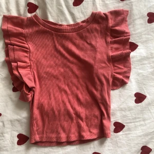 Rosa volangtopp från Zara - Supersöt rosa topp från Zara med volangdetaljer på ärmarna. Toppen är ribbad och har en rund halsringning. Använd få gånger.