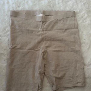 Beige cykelshorts från H&M Basics - Beiga cykelshorts från H&M Basics i storlek L. De har en enkel och clean design med midwaist och är tillverkade i mjuk bomull med lite stretch för extra komfort. Perfekta för chill dagar eller när du vill ha en basic look.