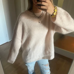 Aprikos rosa mohairtröja från H&M Edition - Supermjuk och fluffig ljusbeige tröja från H&M Edition i mohair- och ullblandning. Oversized fit med rund halsringning och långa ärmar. Perfekt att styla med jeans eller kjol för en chill och trendig look. Aprikos rosa färg 