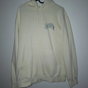 Beige hoodie från H&M med PAUSE-tryck - Snygg beige hoodie från H&M med relaxed fit och stor PAUSE-print i grönt och blått på ryggen. Tröjan har huva med snörning, känguruficka och långa ärmar. Perfekt för chill dagar och streetstyle.