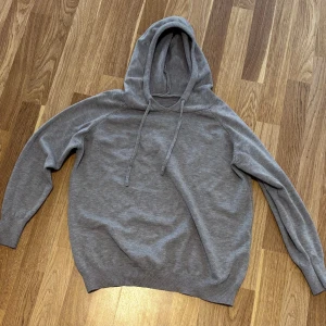 Grå hoodie med huva och snörning - En enkel och stilren grå hoodie med huva och snörning. Tröjan har långa ärmar och ribbade muddar vid ärmslut och nederkant. Perfekt för en chill och avslappnad look. Har använt typ 3 gånger, nypris 600 och mitt pris är 225 😁 