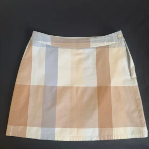 Rutig kortkjol - Superfin kortkjol från s.Oliver i mjuk bomull med rutigt mönster i beige, ljusblått och vitt. Kjolen har dragkedja och knapp i sidan för enkel påklädning. Perfekt för dig som gillar en clean och stilren look.