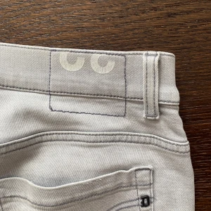 Dondup George - Snygga ljusgrå jeans från dondup i skinny fit-modell. De har klassiska fem fickor, smal passform och är tillverkade i mjukt jeanstyg med stretch. Perfekt för dig som gillar en modern och slimmad look. Passar till sneakers och t-shirt för en clean stil.