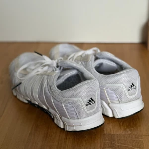 Adidas ClimaCool vita sneakers - Säljer ett par fräscha Adidas ClimaCool sneakers i vitt med mesh-överdel och syntetdetaljer. Skorna har klassiska tre ränder på sidan, snörning och ventilerande material som gör dem riktigt sköna. Perfekt för dig som gillar sportig stil och vill ha något lätt på foten! Sköna och lätta att springa i! 