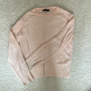 Ljusrosa stickad tröja från MNG - Supersöt ljusrosa stickad tröja från MNG i storlek XS. Tröjan har rund hals och långa ärmar, perfekt för dig som gillar en enkel och clean look. Mjukt material som känns skönt mot huden och passar till många olika outfits.