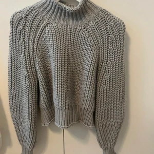 Grå stickad polotröja från H&M - Säljer en chunky grå stickad polotröja från H&M i storlek S. Tröjan har bred ribbad krage, långärmade ärmar och grovstickad struktur.