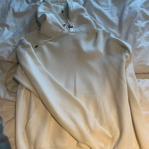Vit hoodie  - Säljer en stilren vit hoodie med huva och snörning. Tröjan har en stor magficka och långa ärmar, perfekt för att chilla eller dra på sig när det är lite kyligt. Mjuk och skön bomullskänsla, passar dig som gillar enkel och clean stil.