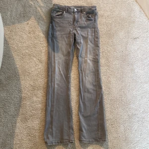 Grå bootcut jeans från LAB Industries - Säljer ett par grå jeans från LAB Industries i storlek 164. Modellen har bootcut-ben och klassisk femficksdesign med knapp och dragkedja framtill. Jeansen är gjorda i mjukt bomullsmaterial och har en snygg, neutral grå färg som passar till det mesta.