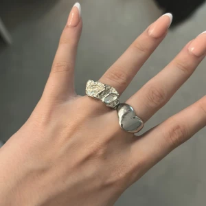 Säljer 3 silverringar - Säljer två unika silverringar. Ena ringen har ett coolt, abstrakt hjärta i blank silverfinish, medan den andra är en stor ring med en detaljerad blomma i silver som verkligen sticker ut. Perfekt för dig som gillar statement-smycken och vill ha något som syns. Alla 3 ringar tillsammans kostar 60kr