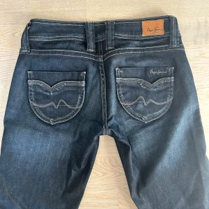 Mörkblå bootcut jeans från Pepe Jeans - Snygga mörkblå jeans från Pepe Jeans med bootcut passform, låg midja och snygga bakfickor. De är i storlek W27/L32  och jag skulle säga att de passar XS/S. Är perfekta i längden för mig som är 170 cm! Midjemåttet är 36 cm och innerbenslängden är 80 cm. Har ni några frågor är det bara att höra av sig! 💕