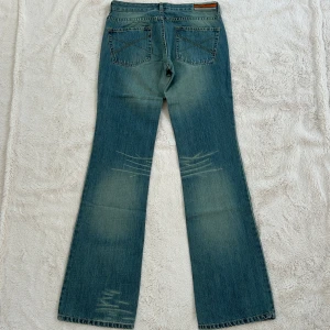 Lågmidjade utsvängda jeans  - Ett par lågmidjade jeans i storlek M. Jeansen är helt nya med prislappar kvar. Rakt över midjemått: 37cm. Gren: 20cm. Total längd: 104cm. Innebenslängd: 85cm. Benslut: 22cm. F52