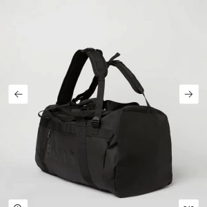 Svart träningsväska Björn Borg 55L - Stor och rymlig svart träningsväska från Björn Borg med 55L kapacitet. Väskan har både handtag och vadderade axelremmar. Perfekt för gymmet eller sportaktiviteter. Väskan har vit text istället för svart. Aldrig använd!