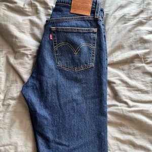 Levi's 501 mörkblå jeans W27 L32 - Säljer ett par klassiska Levi's 501 jeans i mörkblå tvätt. Modellen har rak passform och hög midja, med snygga kontrastsömmar och ikonisk läderpatch bak. Jeansen är tillverkade i slitstarkt bomullsmaterial och har fem fickor samt knappgylf.