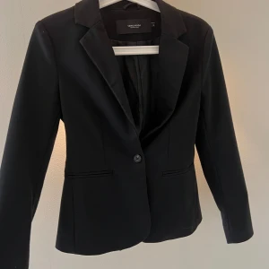 Svart kavaj från Vero Moda XS - Stilren svart kavaj från Vero Moda i storlek XS. Klassisk modell med smal passform.
