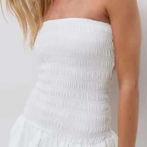 Vit axelbandslös kortklänning med volang - Jättefin vit klänning från Gina. Ordinarie pris 399, priset kan diskuteras. Använd 1 gång säljer pga jag använder inte klänningar❤️