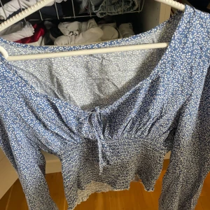Blommig blå blus med knyt - Supersöt blommig blus i blått med vita små blommor. Är i storlek M men passar även S❣️