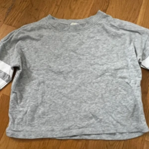Grå sweatshirt med vita ränder - Säljer nu denna tröja från H&M då den blivit för liten!🩶 Använd ett fåtal gånger så den är i fintskick!🩶