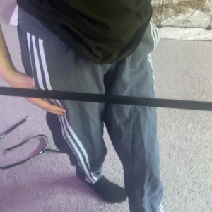 Adidas mörkblå mjukisbyxor med ränder - Säljer ett par mörkblå mjukisbyxor från Adidas med klassiska vita ränder längs sidorna och logga på bakfickan. Byxorna har elastisk midja med snörning och är gjorda i mjukt bomullsmaterial. Perfekta för chill eller träning, loose fit och riktigt sköna.