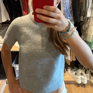 Grå stickad kortärmad tröja - Mysig grå stickad tröja med korta ärmar och rund nacke från Zara. Passformen är normal och materialet känns fluffigt och behagligt mot huden. Den är i bra skick och knappt använd.