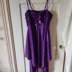 Nattlinne - Ett lila, prickigt nattlinne som man också kan ha till vardags. Jag fick den av en kompis så vet inte exakt vad den är gjord för. Klänningen har tygrosor över bröstet och en rosett i mitten. Kjolen är asymmetrisk och hela klänningen är gjord av ett lätt, tunt lite silkes liknande tyg. Den har ingen etikett så jag vet inte vilket märke det är. Jag skulle säga att den är storlek S eller M.