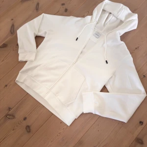 Vit hoodie från Jack & Jones - Tvärfet vit hoodie från Jack & Jones som är perfekt till kalla höst och vinter dagar som kommer då den är gjord av bomull.Helt ny!