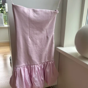 Ljusrosa kort Zara  klänning med volang - Supersöt populär klänning från Zara. Utan axelband och volang nedtill. Klänningen  är i mycket bra skick o endast andvänd en gång💕