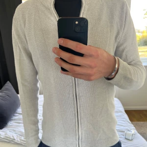 Ljusgrå kofta med dragkedja från Indicode - Säljer en stilren ljusgrå kofta från Indicode i storlek Large. Tröjan har inte använts så mycket så den är väldigt fint skick. Storlek L😃