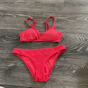 Rosa bikini med leopardmönster - Snygg rosa bikini med sportig topp och smala axelband. Bikinitrosan har ett coolt leopardmönster i struktur som ger extra edge. Perfekt för stranden eller poolen, och tillverkad i mjukt syntetmaterial som torkar snabbt.