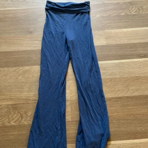 Blåa yoga pants med hög midja - Säljer ett par blå yoga pants med ganska så hög midja och bred linning. Byxorna har en skön och stretchig passform, perfekta för chill dagar eller när du vill vara bekväm. Materialet är mjukt och följsamt, och benen är raka med lite utsvängd nederdel.