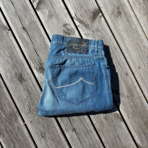 Blå jeans från Jacob Cohen, typ 688 - Säljer ett par schyssta blå jeans från Jacob Cohen, modell Type 688. De har klassisk femficksdesign, snygga kontrastsömmar och en unik patch baktill. Jeansen är slim i modellen och har coola detaljer på insidan av linningen. Perfekt för dig som gillar stilrena och exklusiva jeans. Kom gärna med frågor🙌