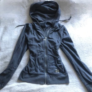 Grå hoodie med guldvingar Victoria's Secret - Supersnygg vintage rare grå hoodie från Victoria's Secret med dragkedja och huva. På ryggen finns stora guldiga paljettvingar. Jackan har två fickor fram och en liten vinge-detalj på ena fickan. 