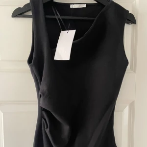 Oanvänd Svart ärmlös klänning från Zara - Supersnygg svart klänning från Zara med asymmetrisk drapering framtill. Passformen är slim och klänningen är i ett mjukt material.❤️