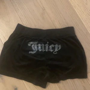 Svarta velourshorts Juicy Couture S - Svarta shorts i mjuk velour från Juicy Couture med glittrande stenar som bildar texten 'Juicy' på baksidan. Pris går att diskutera 