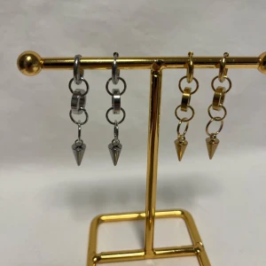 Örhängen med kedjor och konformad detalj - Säljer coola örhängen med kedjor och konformad hängande detalj. Finns i både silver och guld, med chunky ringar och en edgy vibe. Perfekt för dig som gillar att sticka ut med accessoarer som har lite attityd.
