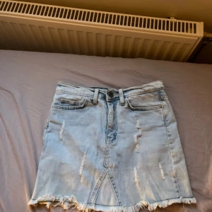 Ljusblå jeanskjol med slitningar och  fransad kant - Säljer pga för liten för mig. Oklart vilken storlek, står ”36” men jag som brukar ha S är den alldeles för liten på. Jag skulle därför gissa att kjolen är storlek XS eller XXS. Märket står inte. 