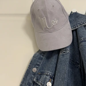Ljusgrå keps från Accessorize - Snygg ljusgrå keps med broderad text 'Moi' framtill. Kepsen har klassisk böjd skärm och är tillverkad i mjuk polyester som ger en lyxig känsla. Perfekt för att addera lite stil till din outfit.