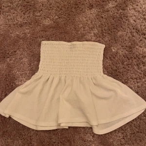 Vit kortkjol/ Topp från Gina Tricot XS - Supersöt vit kortkjol/ Topp från Gina Tricot i storlek XS. Kjolen har en smockad midja som sitter bekvämt och ger en snygg form, samt ett volangigt fall nedtill. Perfekt för att skapa en fräsch och trendig look till sommaren.