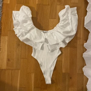 Zara body - Supersnygg vit body från Zara med breda volanger runt axlarna. Storlek S (passar som xs)