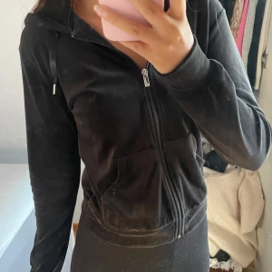 Svart kofta från gina - Säljer en svart hoodie i mjuk velour med huva och snörning. Tröjan har en hel dragkedja framtill och två fickor. Perfekt för chill dagar eller när du vill vara extra comfy. Långärmad och med en snygg, enkel look.💕